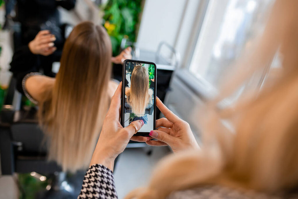 Coiffeur professionnel prenant des photos des extensions de cheveux du client blonde pour la vitrine des médias sociaux - Photo, image