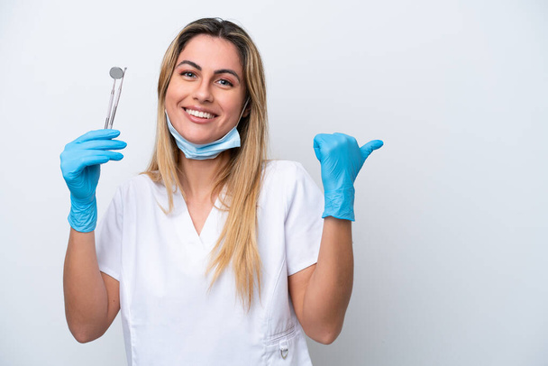 Donna dentista in possesso di strumenti isolati su sfondo bianco che punta verso il lato per presentare un prodotto - Foto, immagini