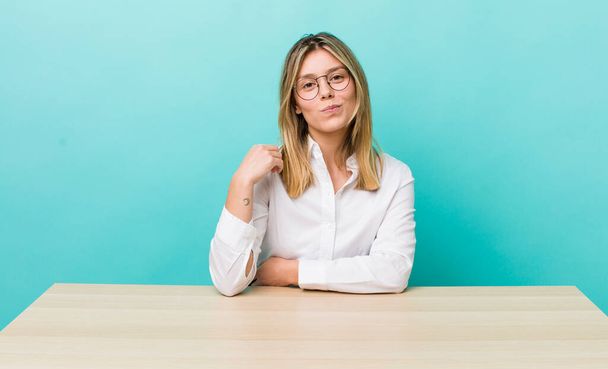 pretty blonde woman looking arrogant, successful, positive and proud. business and desk concept - Photo, image