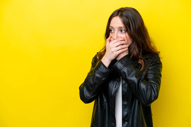 Young caucasian woman isolated on yellow background covering mouth and looking to the side - Photo, image