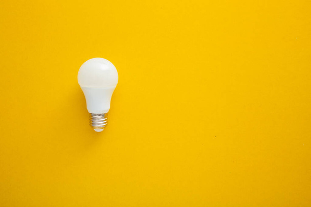 Weiße Glühbirne auf leuchtend gelbem Hintergrund in Pastellfarben. Minimalistisches Konzept, kluges Ideenkonzept, - Foto, Bild