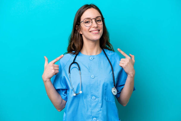 Young surgeon doctor woman isolated on blue background giving a thumbs up gesture - Φωτογραφία, εικόνα