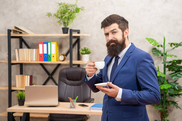 smiling brutal ceo in businesslike suit has lunch break with coffee cup at the office, businessperson - Foto, Imagen