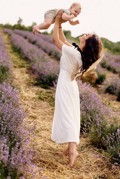 attractive young mother playing with her baby in a lavender field - Фото, изображение