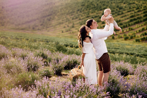 Mooie jonge familie in een lavendelveld brengt de dag door - Foto, afbeelding