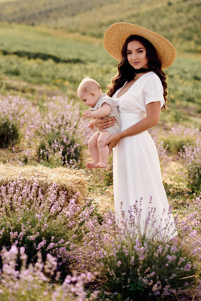 attractive young mother playing with her baby in a lavender field - Foto, Imagen