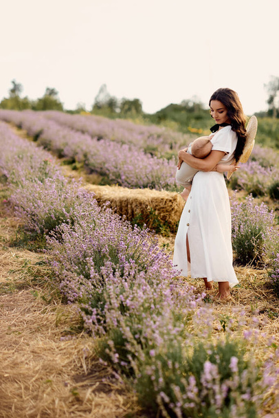 beautiful young mother breastfeeding baby in a lavender field - Фото, изображение