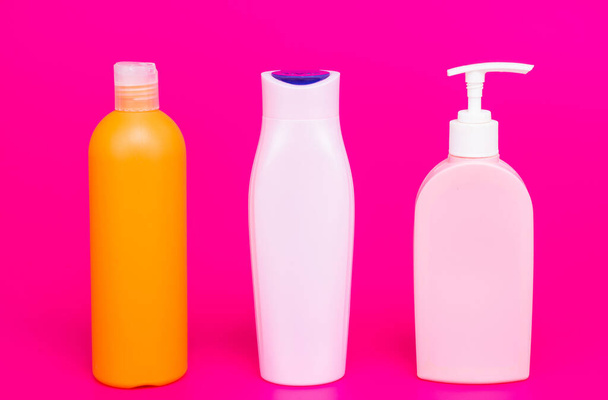 Pump and flip cap plastic containers for liquid cosmetic products in row pink background copy space, bottles - Φωτογραφία, εικόνα