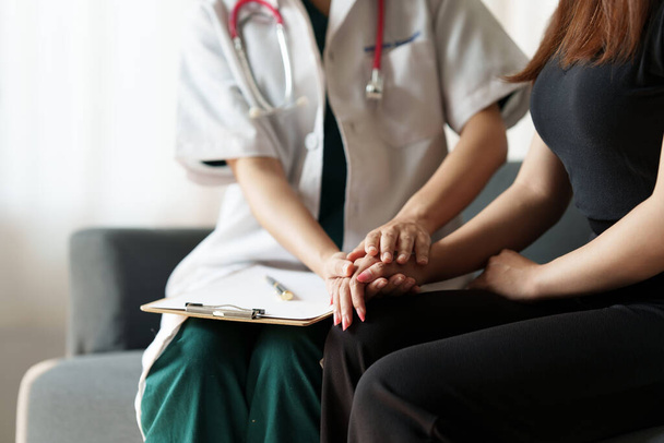 Γιατρός κρατήσει το χέρι του ασθενούς και δίνοντας παρηγοριά και συμβουλές στην κλινική. - Φωτογραφία, εικόνα