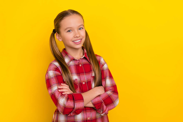 Photo of charming funny schoolgirl wear checkered shirt arms crossed empty space isolated yellow color background - Фото, зображення
