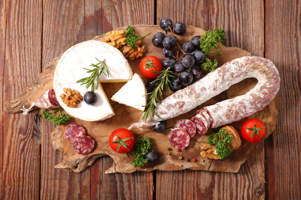 cheese,  salami and grapes on board - Фото, зображення