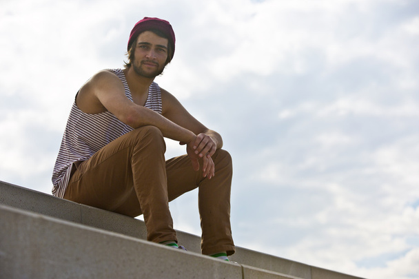 Skateboarder sitting on concrete steps - Fotoğraf, Görsel