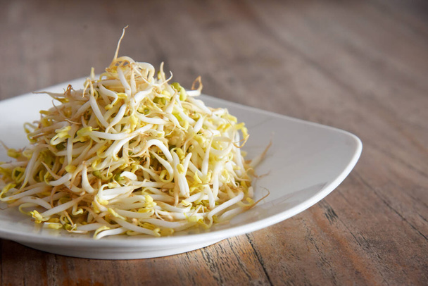 Fresh green bean sprouts,placed on white palte, on brown wooden background - Photo, Image