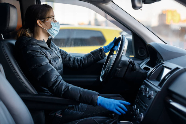 Bella donna caucasica con occhiali, maschera medica anti virus e guanti di lattice blu alla guida di un'auto con le mani sul volante. Protezione dall'infezione da Corona COVID-19. Concetto sanitario - Foto, immagini