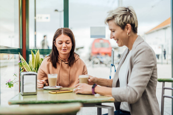 Dvě kamarádky pijící kávu a užívající si čas v kavárně na nádraží - Fotografie, Obrázek