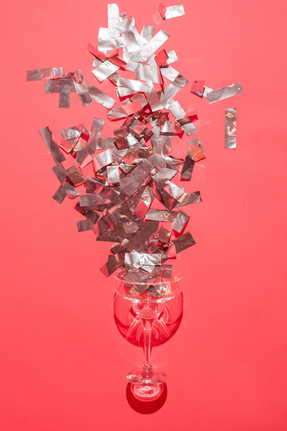 Studio shot of a glass of wine isolated on pink background closeup with celebration confetti. Wine concept. - 写真・画像