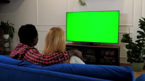 Green screen TV multiethnic family couple embrace watching movie series on TV - Footage, Video