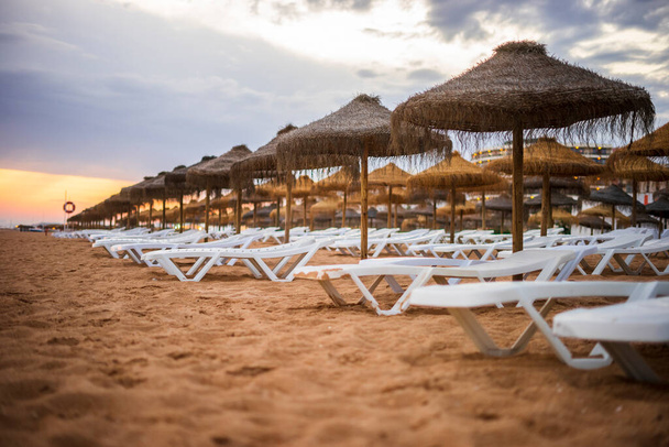 Beau coucher de soleil coloré sur chaises longues et parasols à Vilamoura, Algarve, Portugal - Photo, image