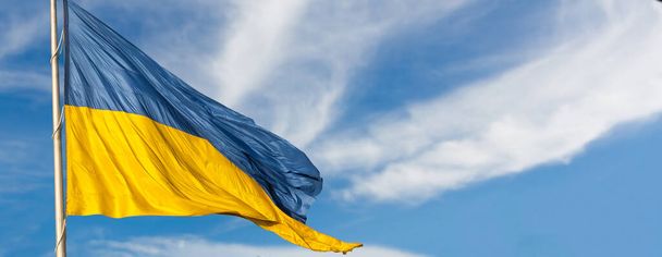 Grote nationale vlag van Oekraïne vliegt in de blauwe lucht. Groot geel blauw Oekraïense staatsspandoek. Onafhankelijkheid, vlag, Dag van de Grondwet, Nationale feestdag, tekstruimte. - Foto, afbeelding