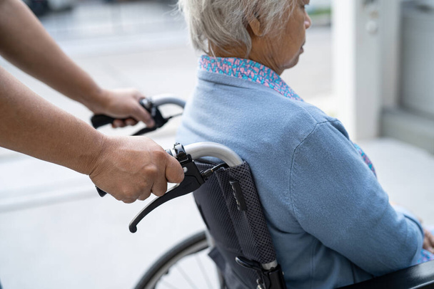 Bakıcı, Asyalı yaşlı ya da yaşlı kadın hasta bakıcı, hemşire hastanesi koğuşunda tekerlekli sandalyede oturuyor, sağlıklı, güçlü bir tıbbi konsept. - Fotoğraf, Görsel