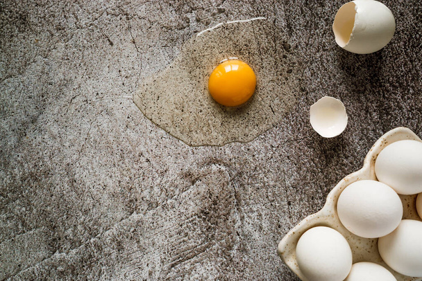 Taze çiftlik beyaz tavuk yumurtaları, yakın plan, bir kırık, görünür yumurta sarısı. Gri, nötr beton bir zeminde duruyorlar. metin için yer - Fotoğraf, Görsel