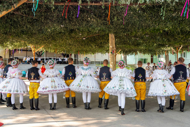 チェコ共和国ラクヴィツェ- 2021年6月。祝いの美しい女性と男性のダンサー.伝統的なモラヴィアの饗宴.伝統的なモラヴィア民族衣装を着たパレードの若者たち. - 写真・画像