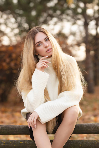 Atrakcyjna blondynka w białym swetrze na tle jesiennych kolorów - Zdjęcie, obraz