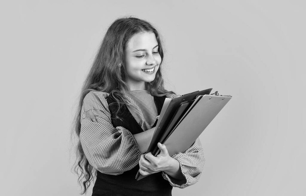 happy looking kid girl with document folder, concentrated on work - Zdjęcie, obraz