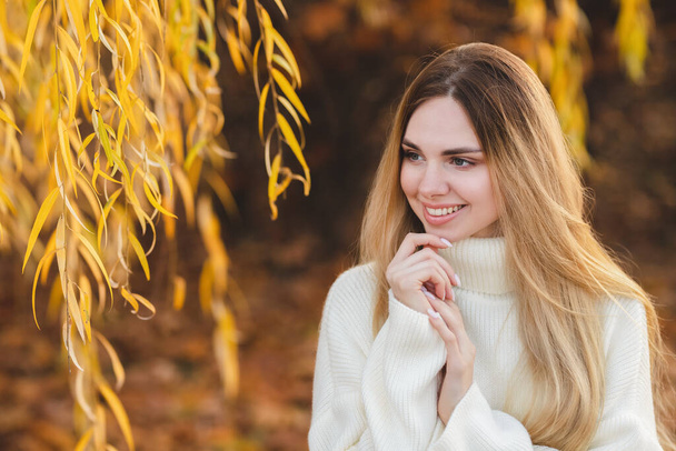 Çekici bir sarışının harika bir gülümsemesi olan portresi. Beyaz kazaklı kız. - Fotoğraf, Görsel