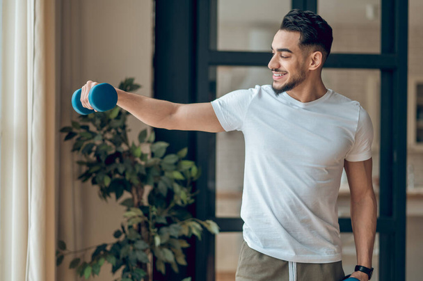 A man with dumbbells having a home workout - Φωτογραφία, εικόνα