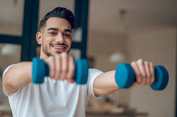 A man with dumbbells having a home workout - Photo, Image