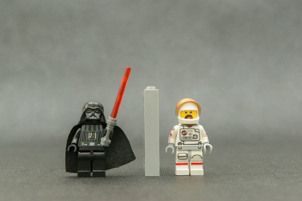 Bauru, Brasilien. 15. September 2019: Darth Vader hält sein rotes Säbellicht in die Höhe und zeigt einen verängstigten Astronauten mit erhobenen Händen. Lego-Minifiguren werden von der Lego Group hergestellt. - Foto, Bild