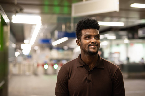 Fiatal, jóképű fekete férfi portréja az állomáson éjszaka - Fotó, kép