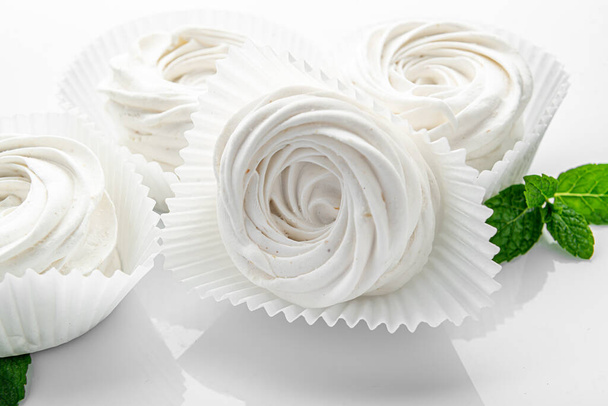 Kleine witte meringues op een witte achtergrond. meringue snoep - Foto, afbeelding