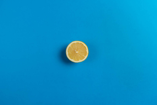 Верхний вид на половину лимона изолированы на голубом фоне, цитрусовые фрукты с большим количеством витамина С - Фото, изображение