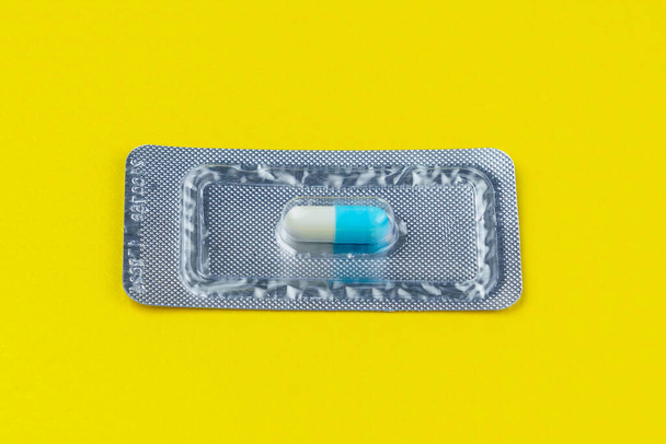 Buborékcsomagolás vagy egy nagyon fontos és drága tablettát vagy tablettát tartalmazó csomagolás. Sárga háttér. Szelektív fókusz és másolás. Gyógyászat és farmakológia. - Fotó, kép