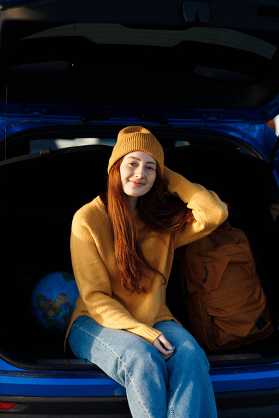 cute casual woman ready for travel with globe in car  - Фото, изображение