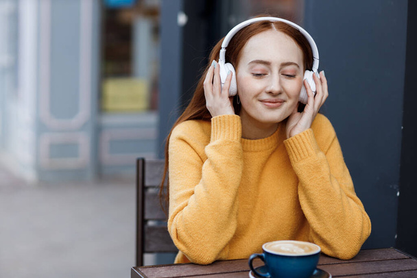 cute woman with headphones in cafe outdoor - Фото, изображение