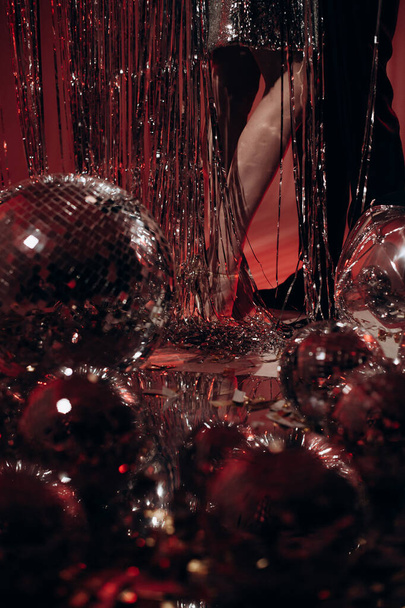 piernas de una pareja enamorada en una fiesta entre lanzadores de discos e iluminación roja - Foto, imagen