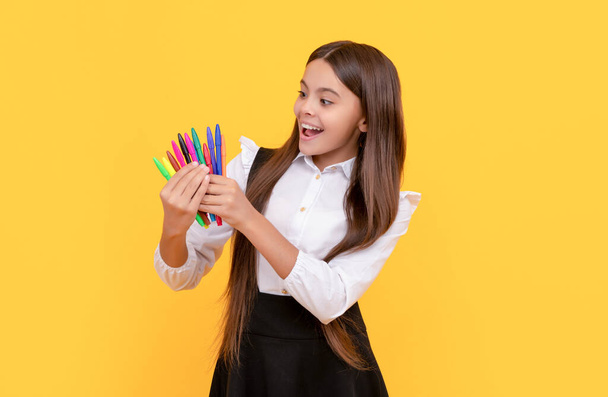 Ευτυχισμένο κορίτσι παιδί κρατήσει τσόχινο-άκρες κίτρινο φόντο, γραφική ύλη σχολείο - Φωτογραφία, εικόνα