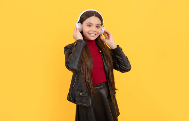 smiling kid in earphones on yellow background, education online - Photo, Image
