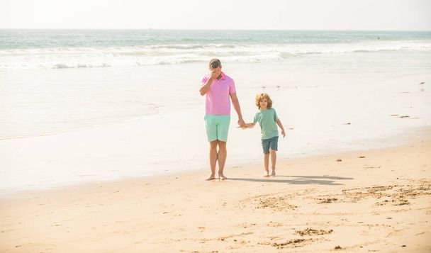 spacer ojca i syna po letniej plaży. weekend podróży rodzinnych i wakacje. - Zdjęcie, obraz