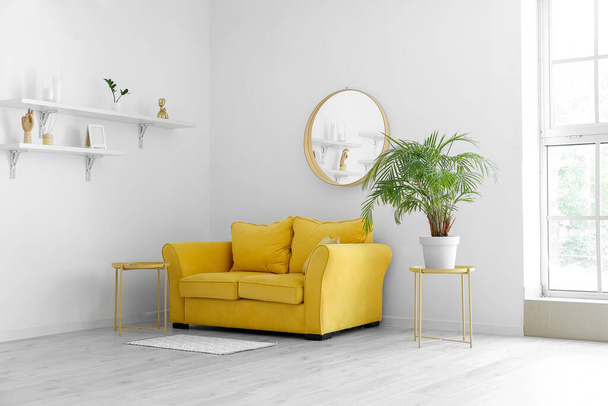 Innenraum eines hellen Wohnzimmers mit gelbem Sofa und Zimmerpflanze - Foto, Bild