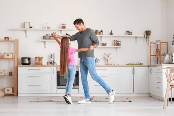 Happy man and his little daughter dancing in kitchen - Фото, изображение