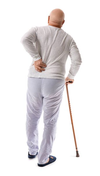 Hombre mayor con bastón que sufre de dolor de espalda sobre fondo blanco - Foto, imagen