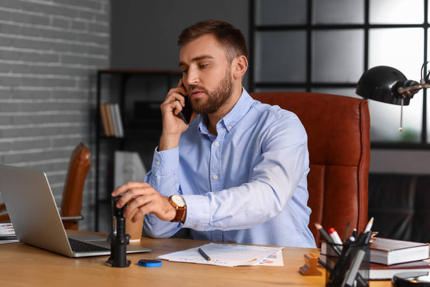 Нотариус-мужчина разговаривает по телефону в офисе - Фото, изображение