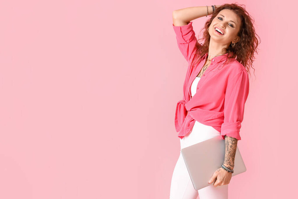 Stílusos tetovált nő laptop rózsaszín háttér - Fotó, kép