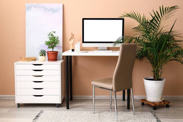 Interior of room with modern workplace and houseplant near color wall - Photo, Image