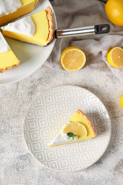 Placa con trozo de sabroso pastel de limón y frutas frescas sobre fondo claro - Foto, Imagen