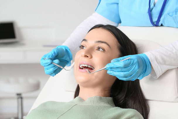 Krásná žena se zubními rovnátka na návštěvě zubaře na klinice - Fotografie, Obrázek